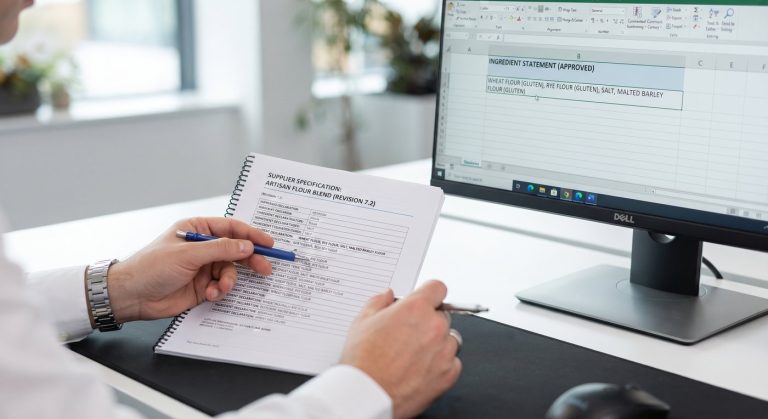 QA reviewing a supplier specification against the approved ingredient declaration on screen