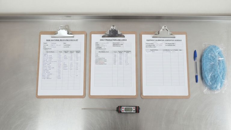 Receiving checklist, line check and calibration schedule on clipboards with a probe thermometer