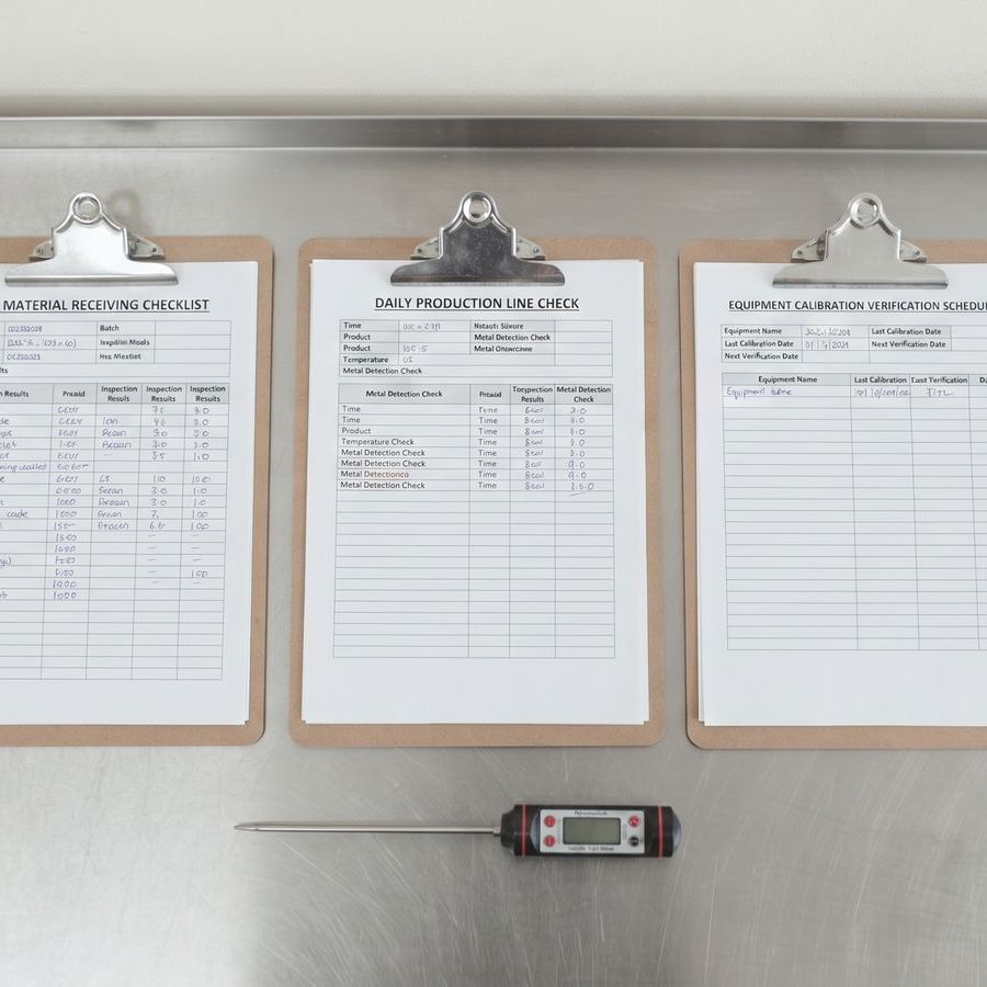 Receiving checklist, line check and calibration schedule on clipboards with a probe thermometer